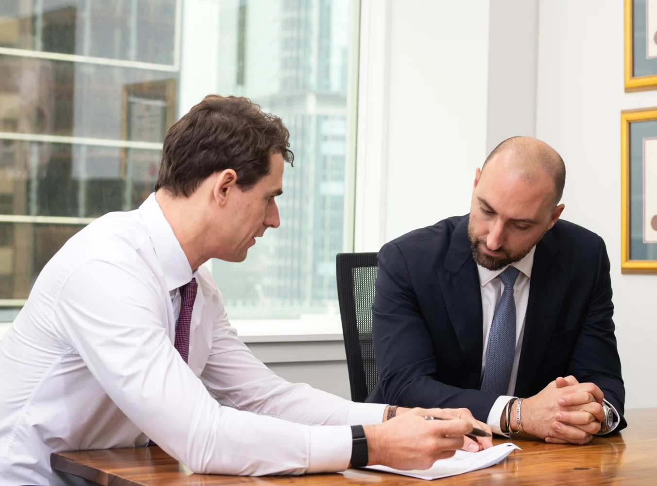 Two business professionals reviewing a commercial contract, discussing legal terms for business compliance.