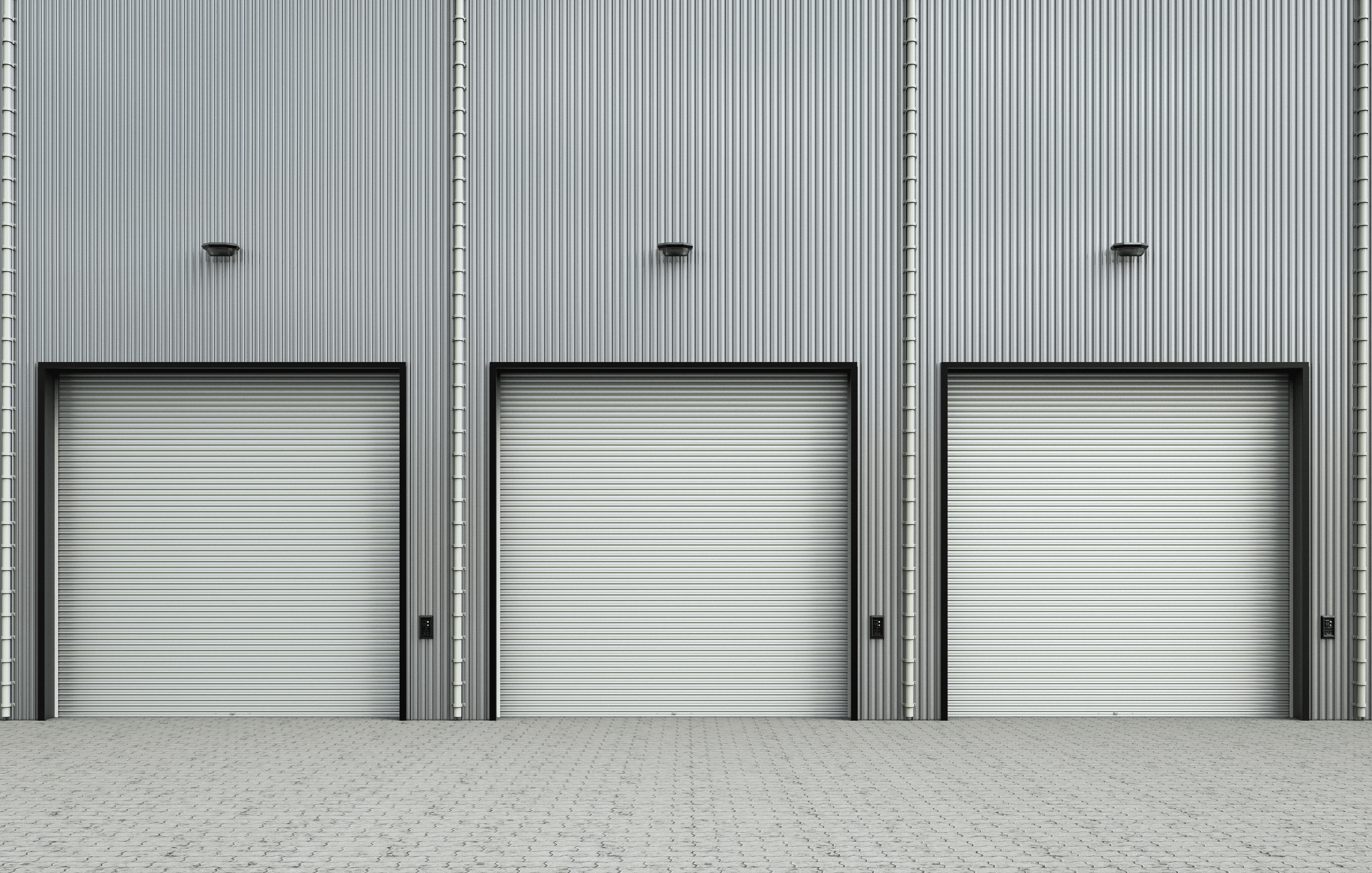 Row of three industrial rolling steel doors installed in a silver corrugated metal warehouse facade. High-performance commercial bay doors featuring black frames and a minimalist industrial design for logistics and shipping facilities.