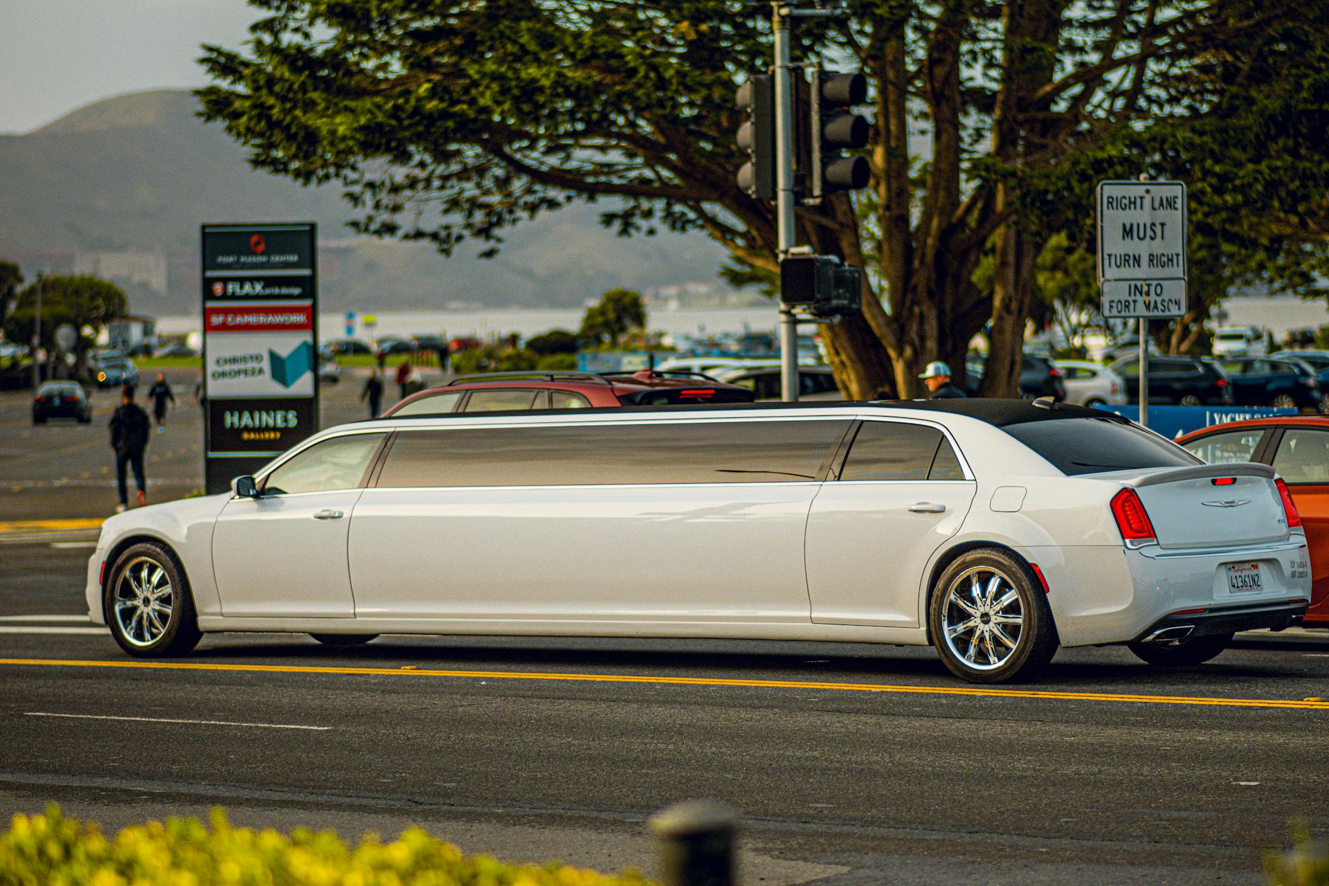White luxury limousine parked on city street, showcasing spacious interior for group celebrations and events, ideal for party bus service.