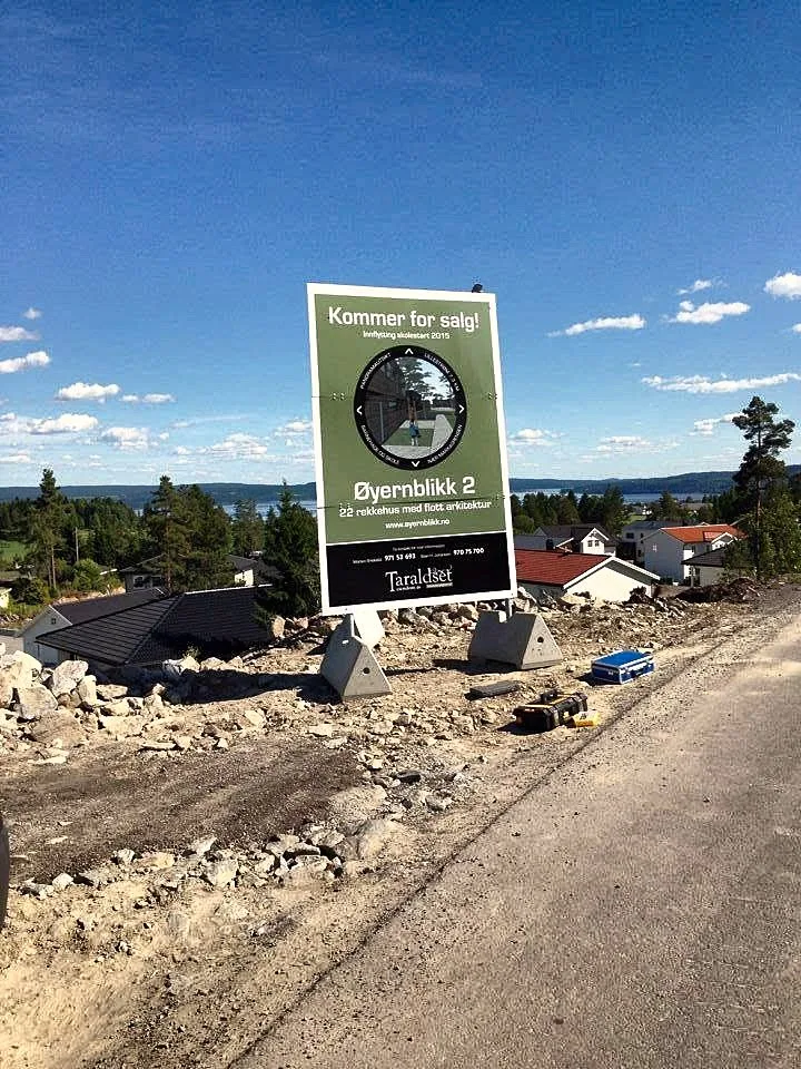 Byggeskilt med teksten «Kommer for salg» ved et boligfelt under bygging