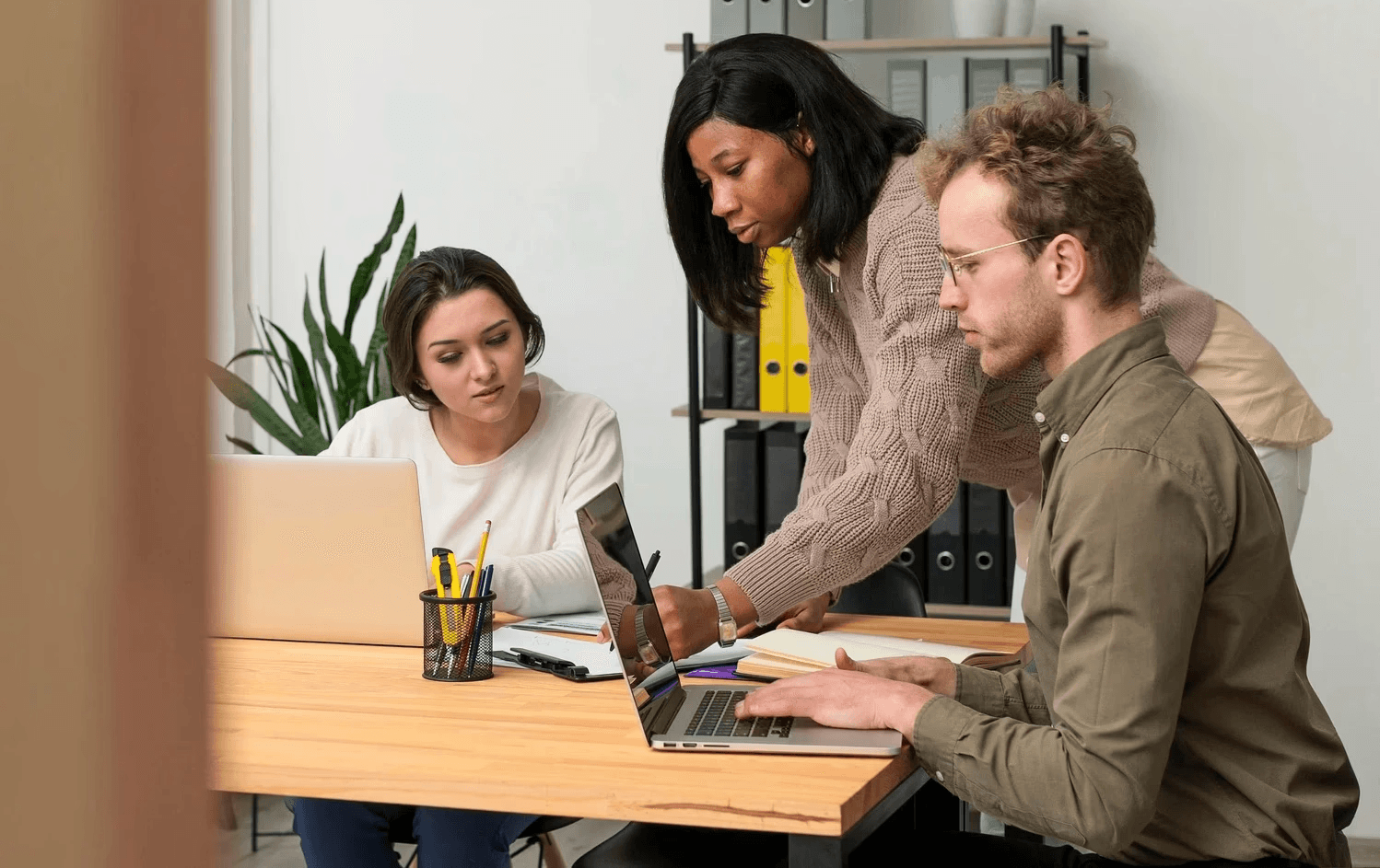 duas mulheres e um homem sentados na mesa de um escritório fazendo planos no computador e definindo objetivos e metas