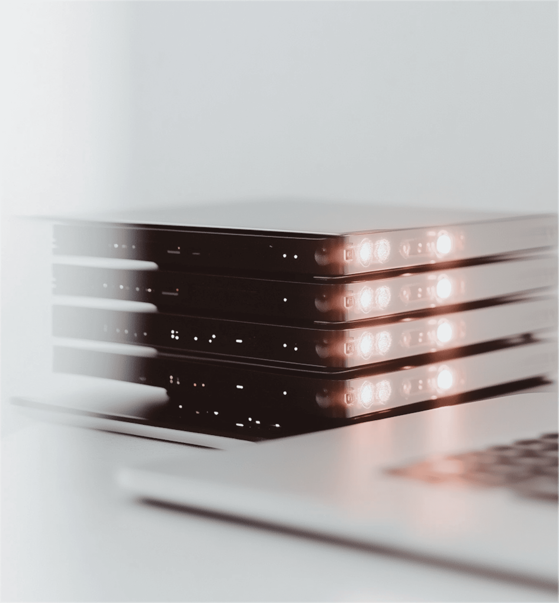 Network switches with glowing lights beside a laptop in a clean tech setup.
