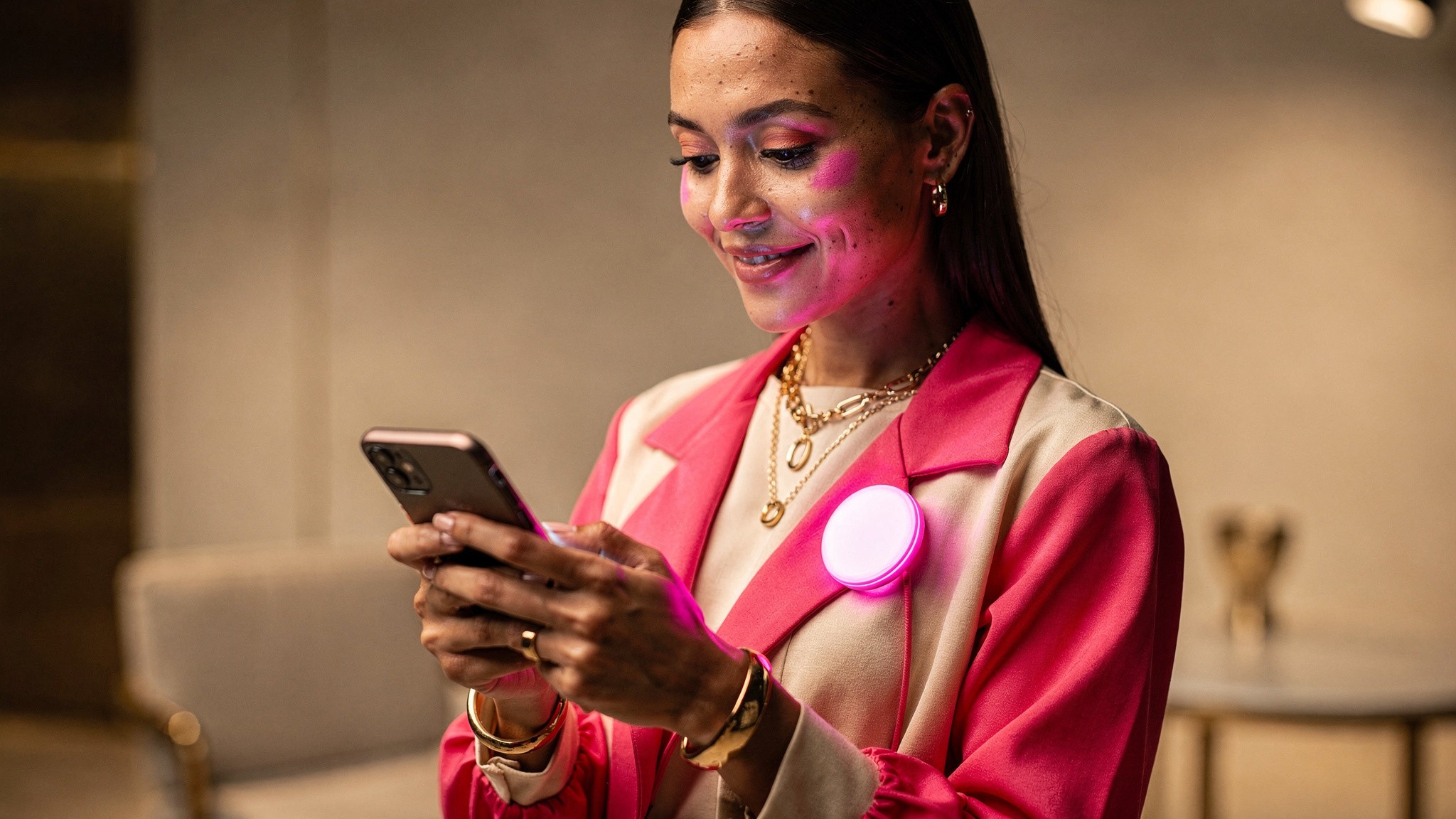 Creator looking at her phone with a satisfied smile, a soft pink badge glow on her face