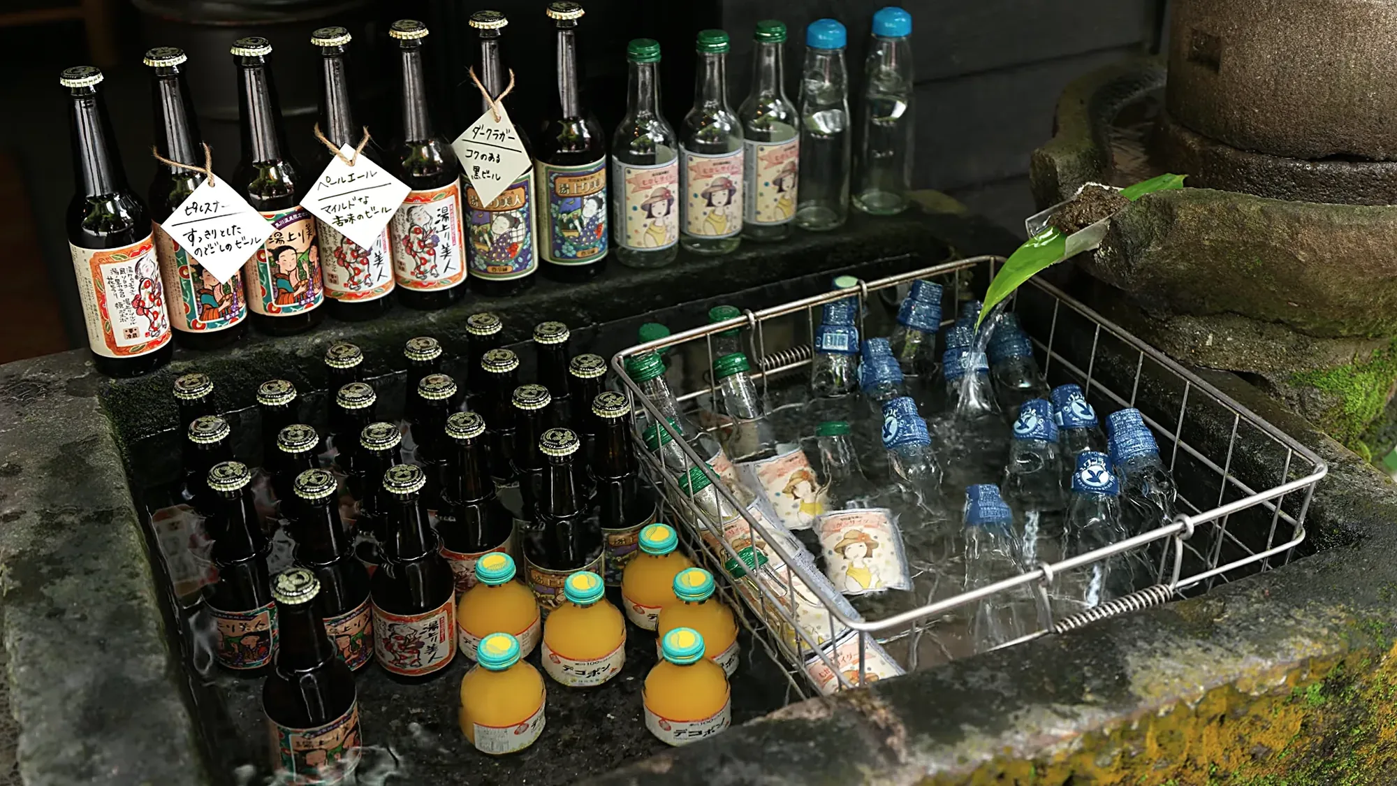 Bottles of local drinks and juice cooling in a water bath at a shop in Kurokawa Onsen