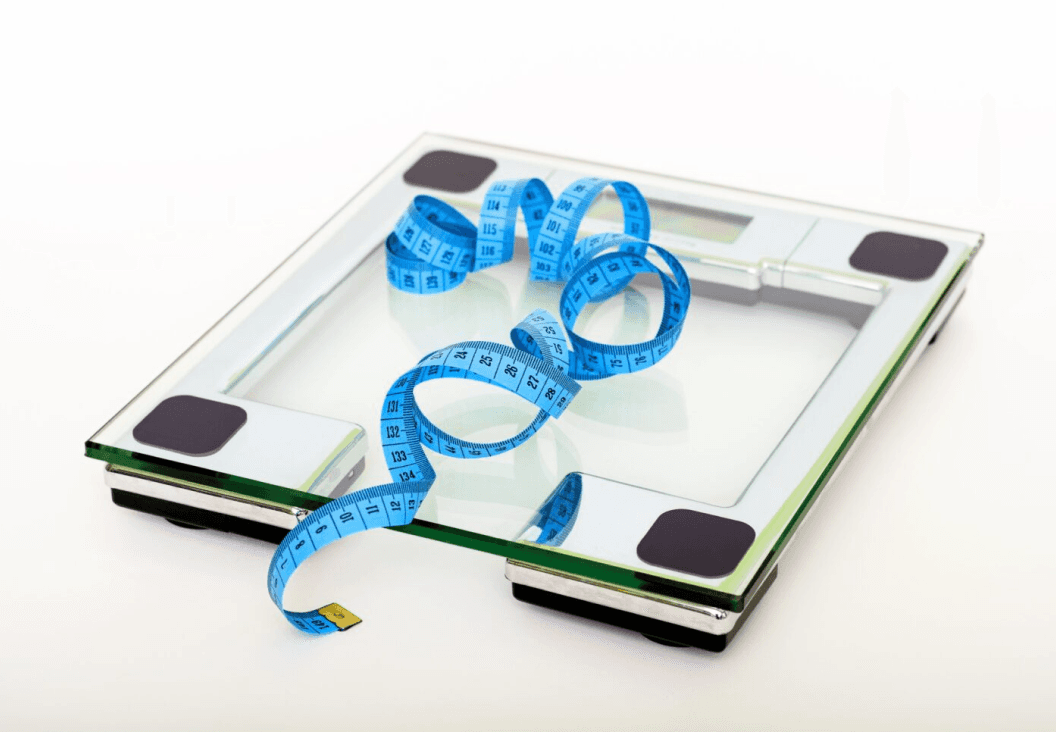 bathroom scale and measuring tape representing weight loss helping improve men’s health