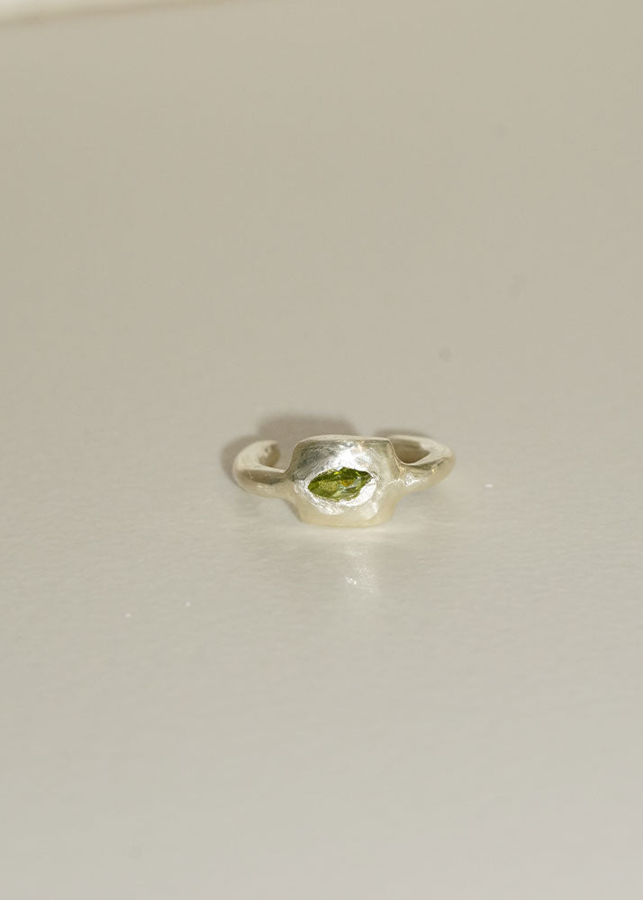 Silver ring with a green stone on a light gray background