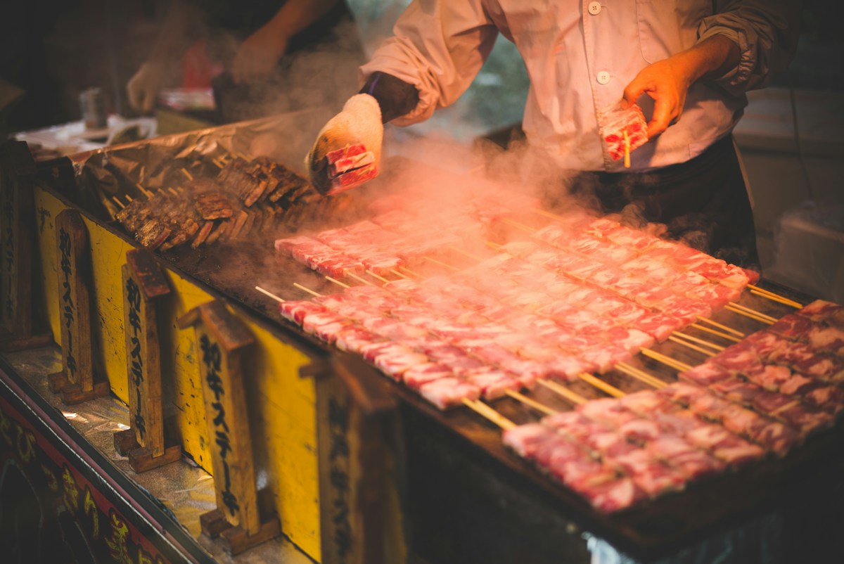 A vendor grilling skewers at a Japanese street food stall