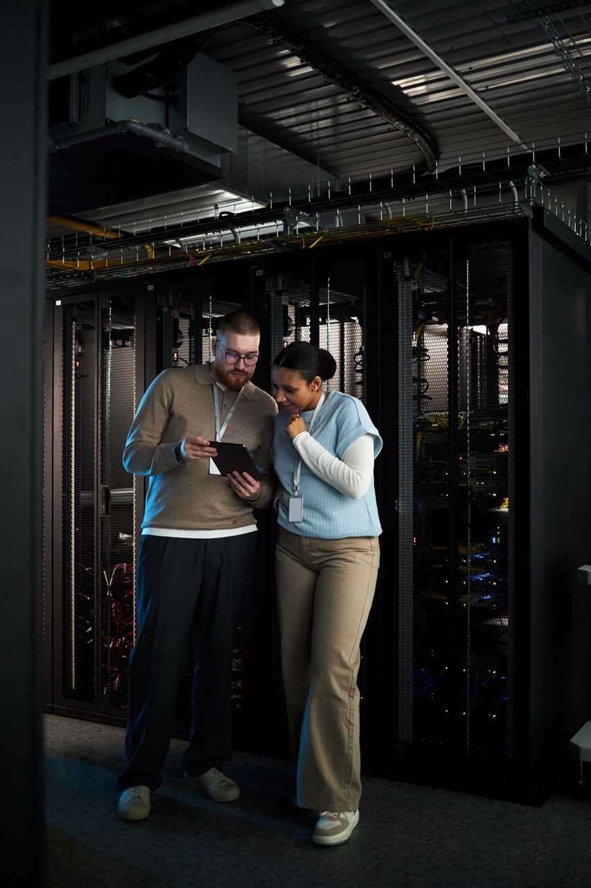 Two people looking at tablet in front of a server data center