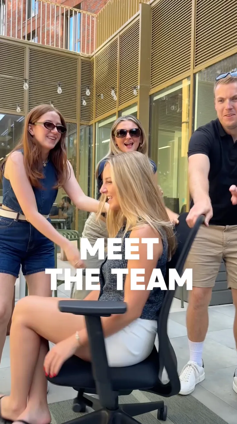 Team members laughing around an office chair, captioned Meet the team