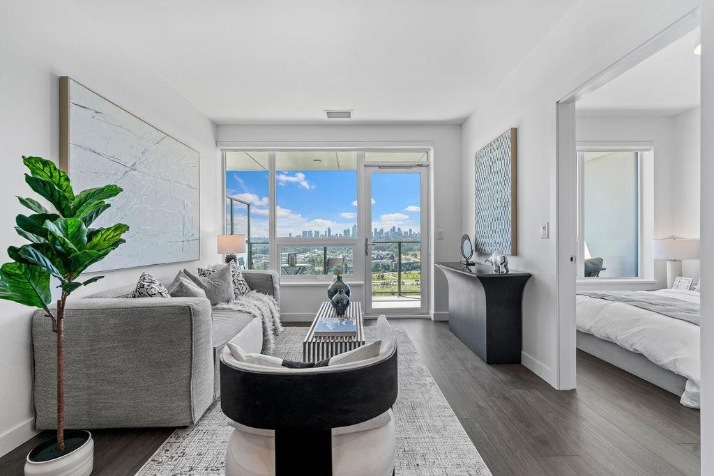 Modern living room with large windows, white decor, a circular table, and a green plant, offering a bright atmosphere.