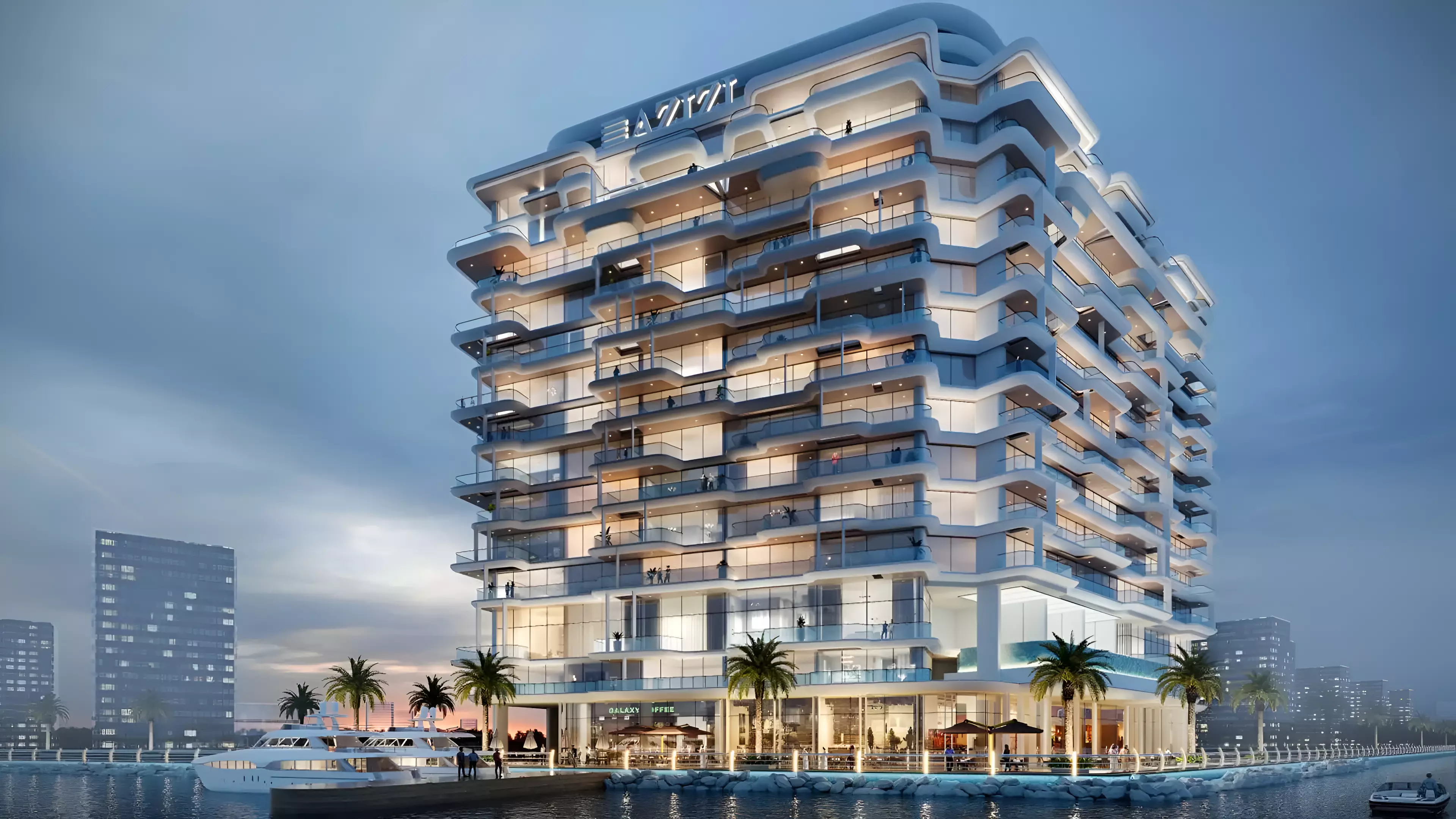 Illuminated exterior of Azizi Wasel apartments in Dubai at night, featuring curved balconies and waterfront dining spaces.