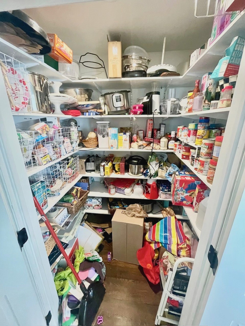 messy walk in pantry with lots of baskets and cans