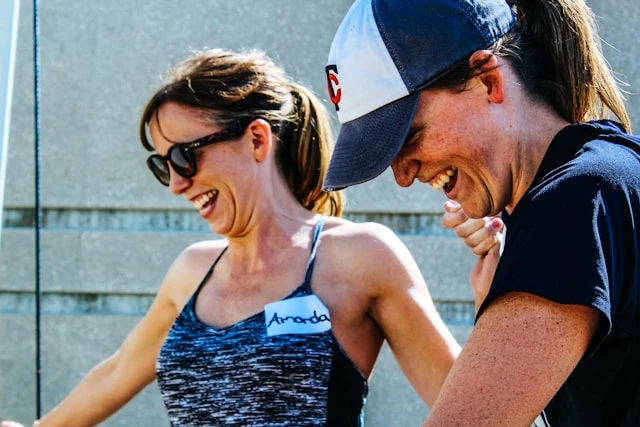 Woman laughing in sunlight during an outdoor workout with a training partner