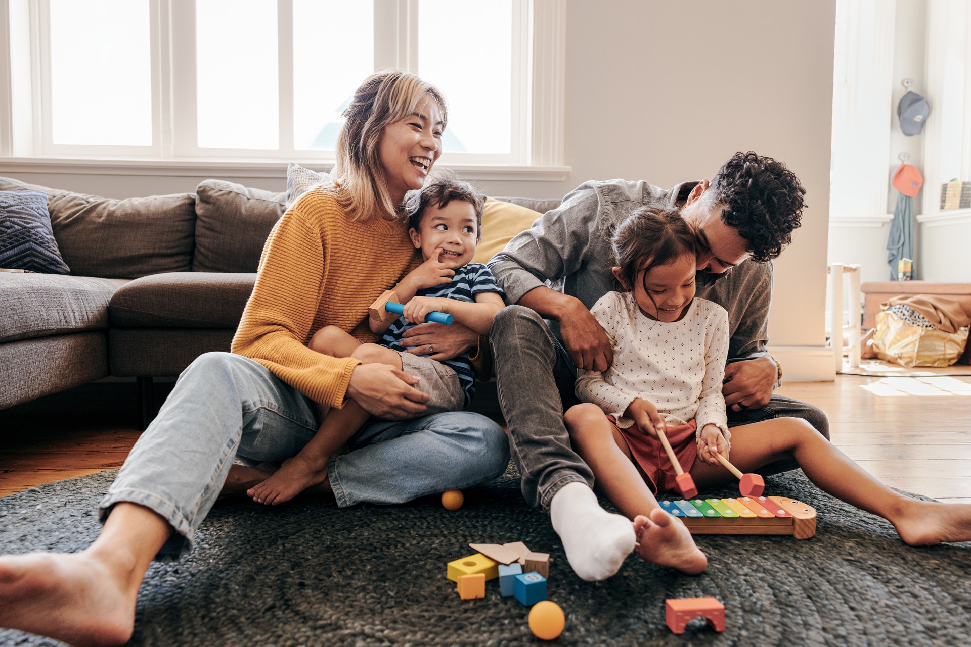 Diverse Familie mit zwei Kindern spielt im Wohnzimmer