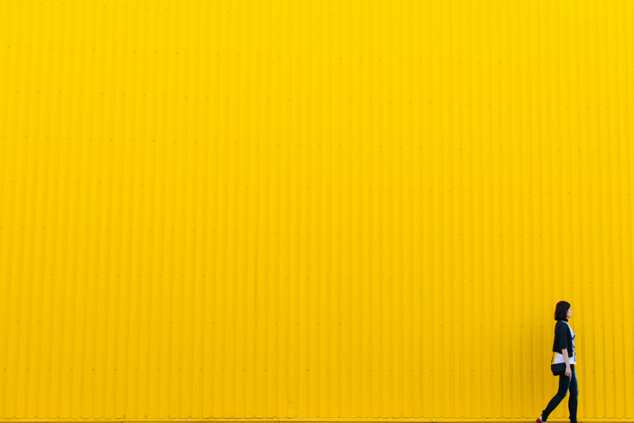 Girl Walking by Yellow Wall - Preppy Colors