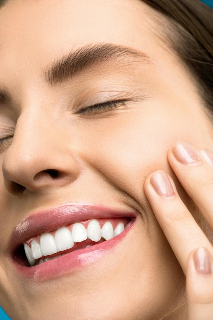 لقطة مقربة لوجه امرأة تُظهر ابتسامة هوليود سمايل بعد تركيب فينير الأسنان.