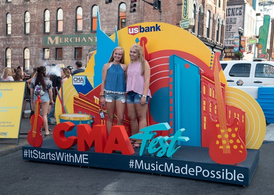 Festivalgoers pose at a colorful CMA Fest photo op installation in downtown Nashville, promoting fan interaction, brand visibility, and social media sharing at the country music event.