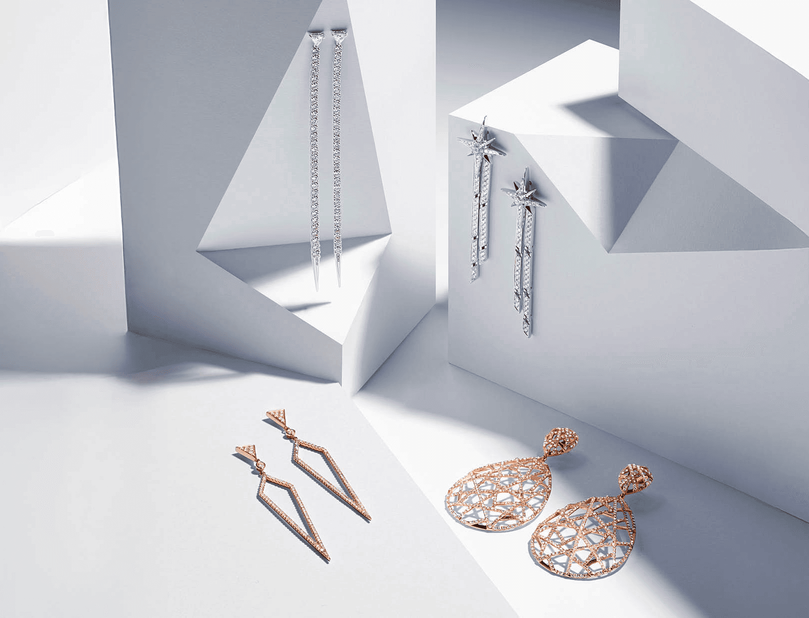 Elegant gold and silver earrings on geometric white background, showcasing luxury jewelry collection.