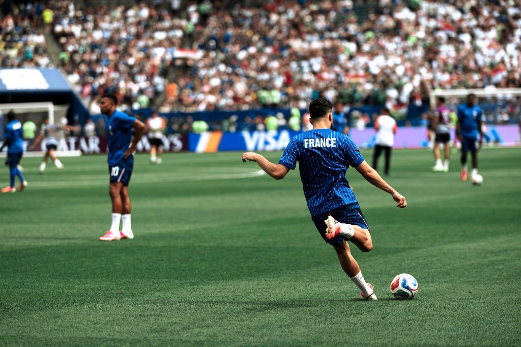 A France player strikes the ball in front of a packed stadium crowd at the 2026 World Cup