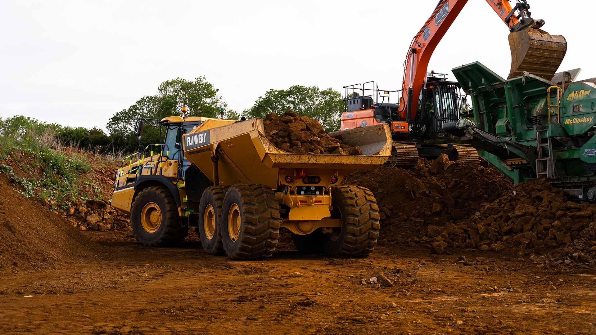 ETC articulated dumper receiving soil from excavator and rock crusher during groundworks operation