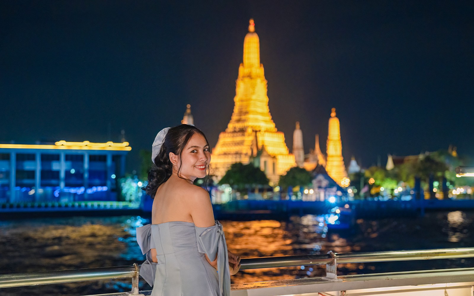Cruise on Chao Phraya River with Wat Arun illuminated at night in Bangkok.