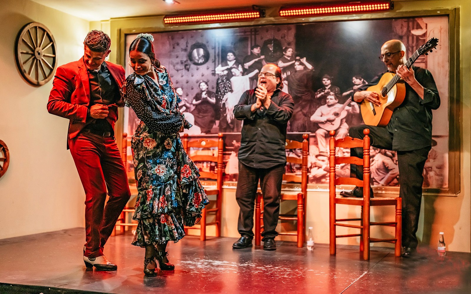 Flamenco dancers performing on stage with guitarist and clapping audience, Spain.