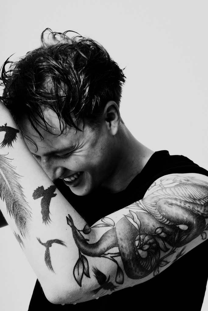 Black-and-white image of the young man looking down and laughing with arm in the foreground