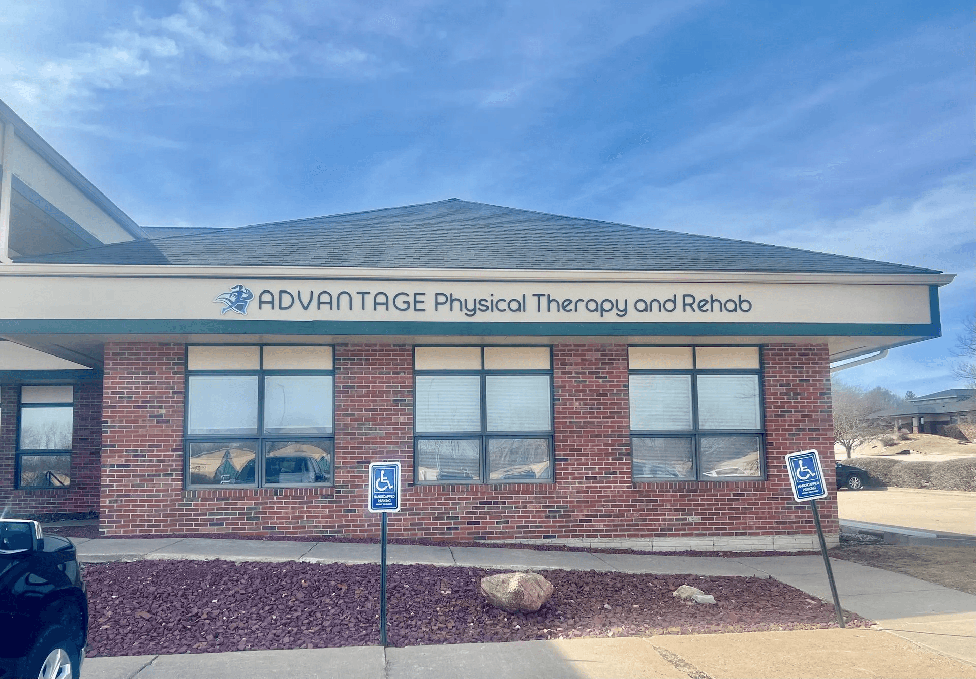 The professional brick exterior of Advantage Physical Therapy and Rehab, featuring an accessible entrance and designated patient parking.