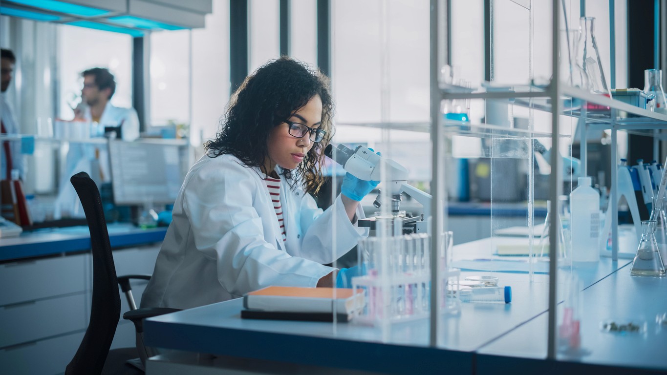 A brown haired woman examining a lab specimen with a microscope