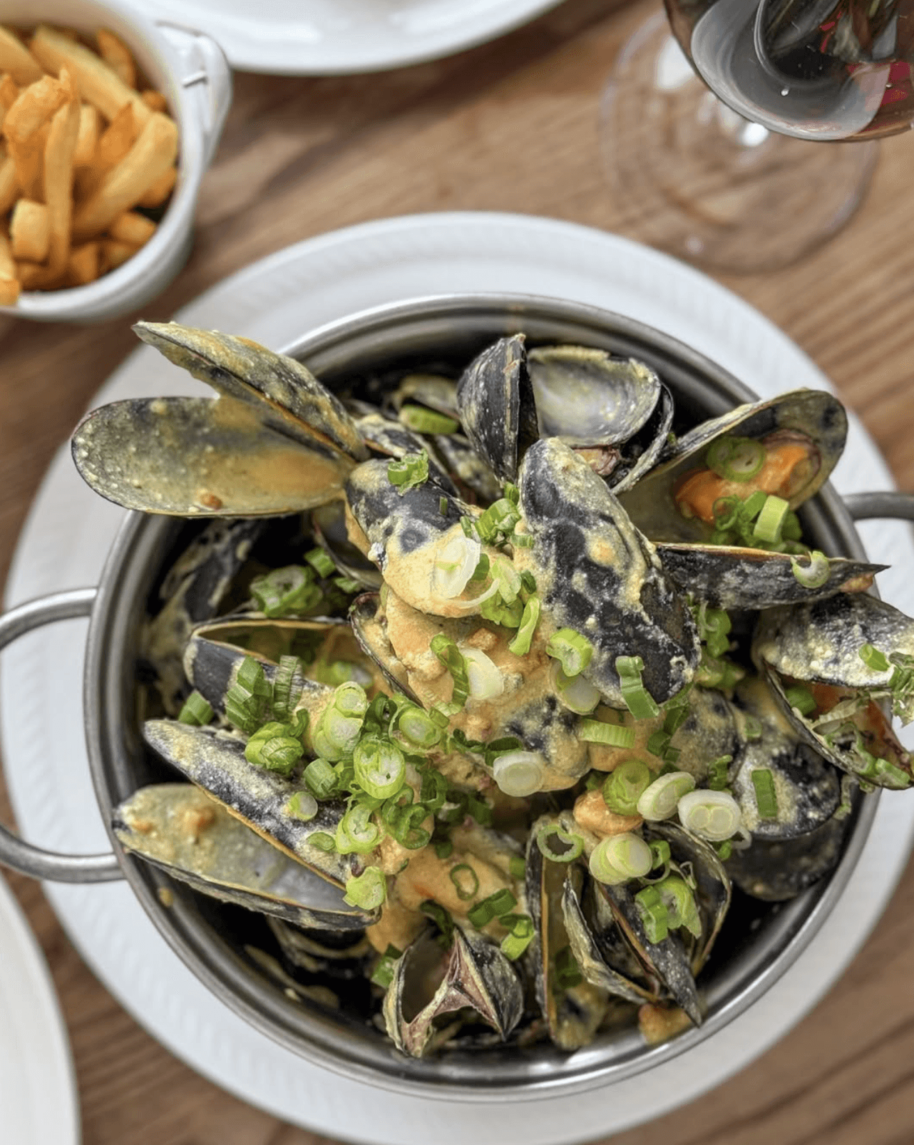 Chef preparing a dish at a rustic wooden table with fresh ingredients.