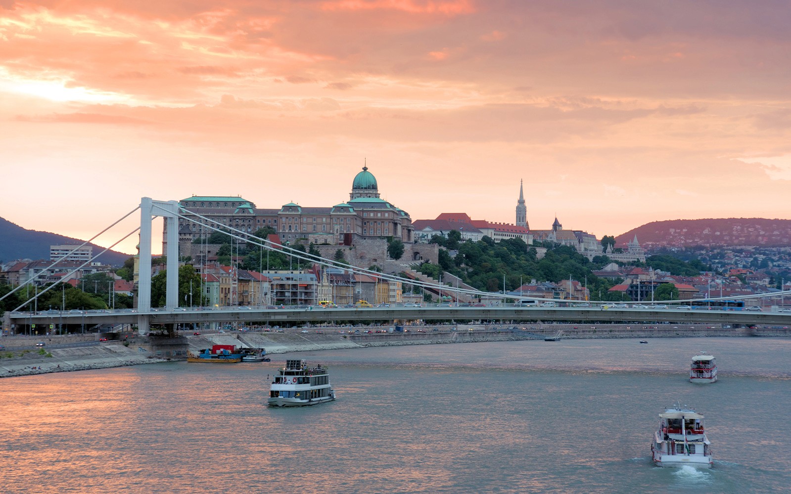 Donaufluss-Kreuzfahrt mit Blick auf die Burg von Buda und die Elisabethbrücke in Budapest bei Sonnenuntergang.