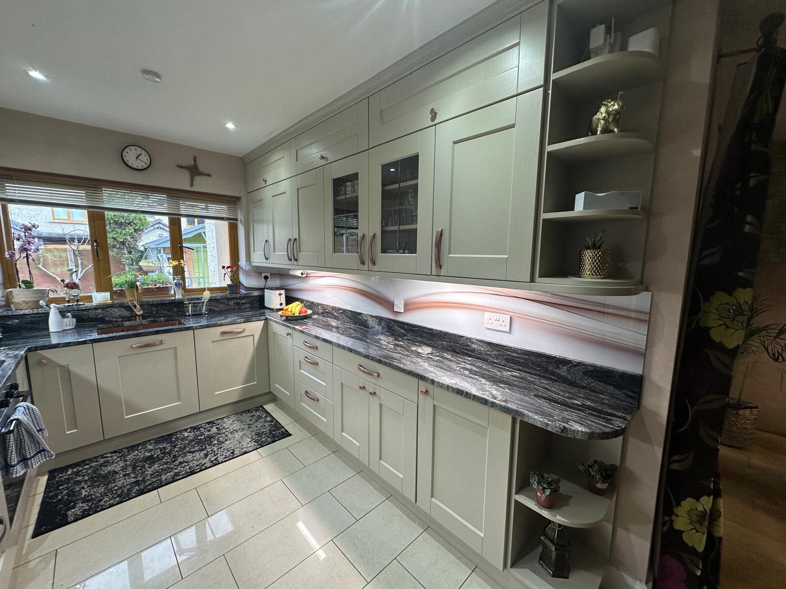 Modern kitchen with a wooden dining table, white chairs, and a hanging light fixture above.