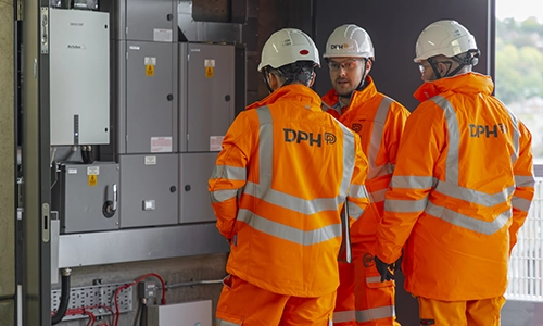 Modern glass building with illuminated interior and reflections at sunset