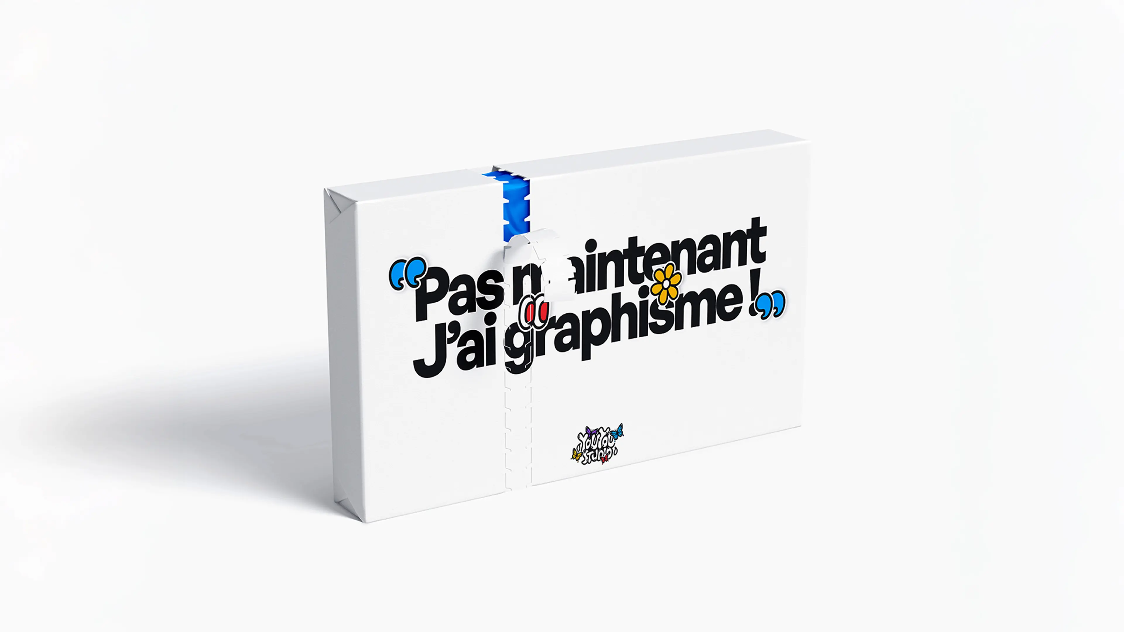 Boîte packaging blanche Youyou Studio avec typographie noire Pas maintenant J'ai graphisme décorée d'icônes colorées - guillemets bleus, yeux rouges, fleur jaune et papillons bleus, logo Youyou Studio en bas à droite