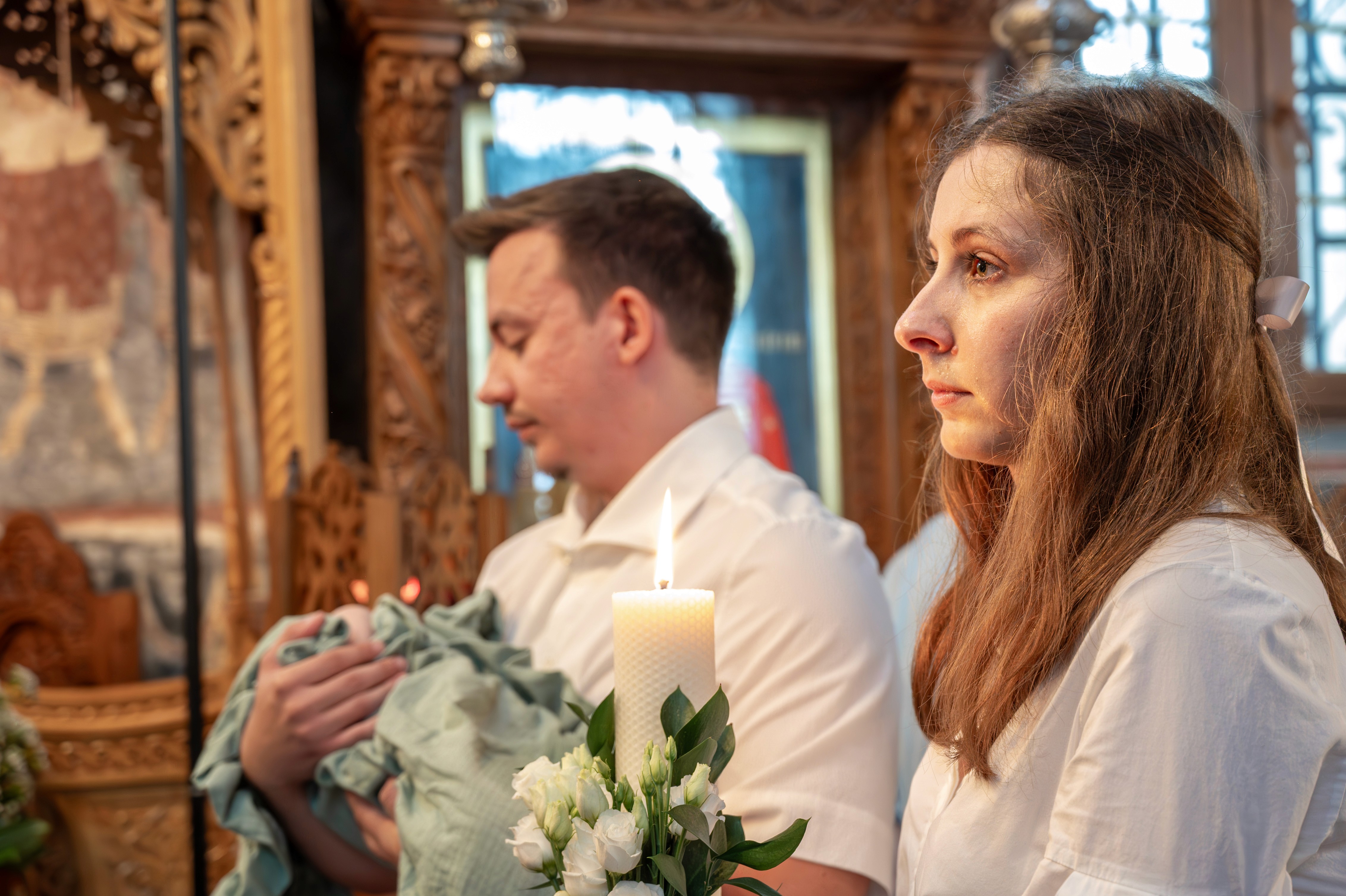 Părinții ținându-și bebelușul în timpul slujbei de botez ortodox — fotografie emoționantă realizată de fotograf botez București.