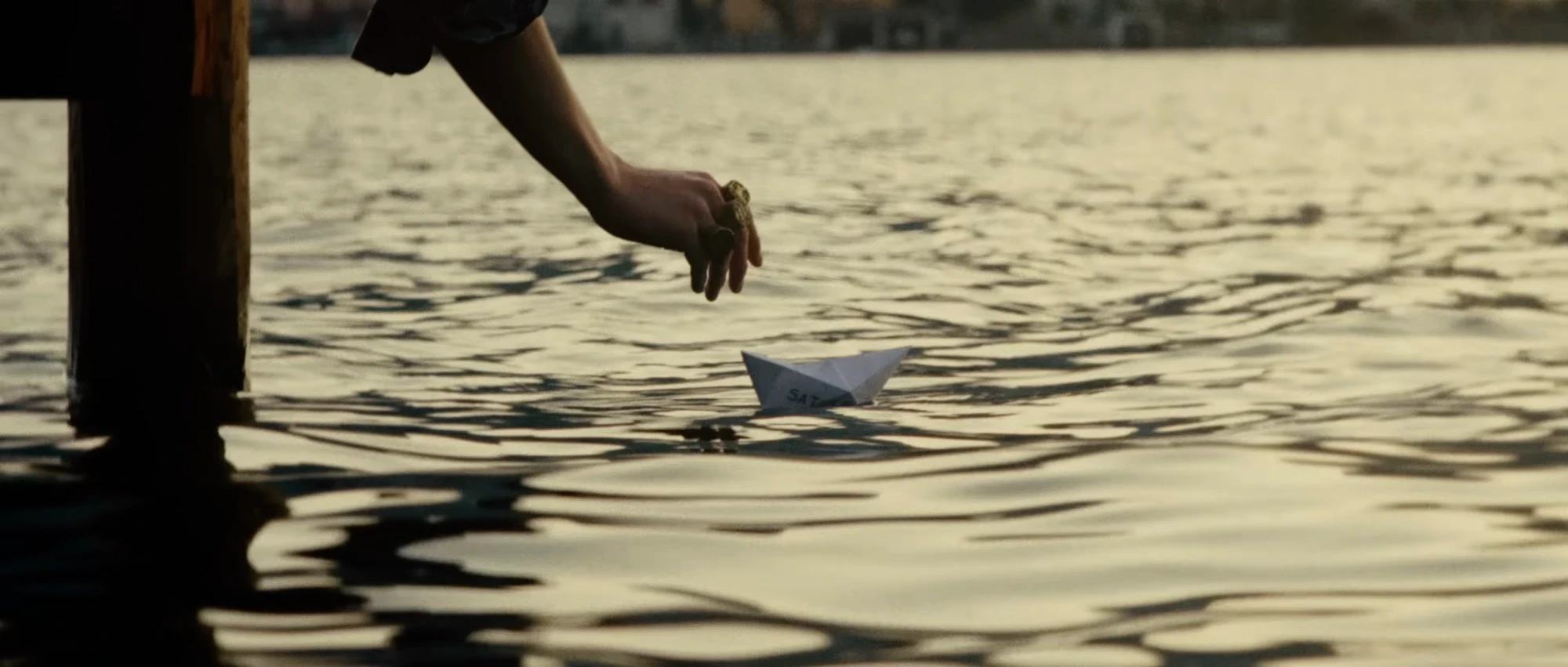 Hand reaching towards rippling lake water