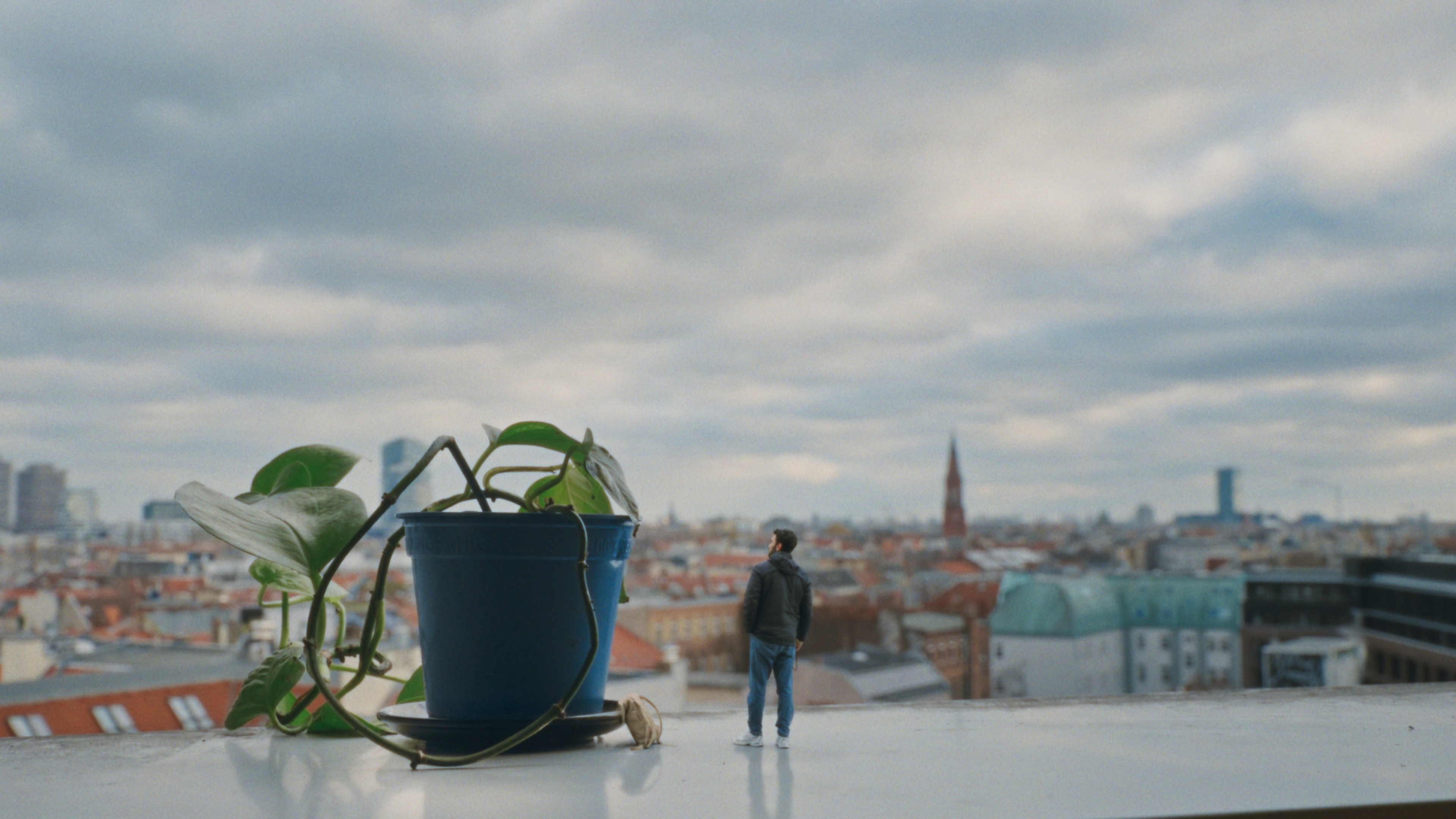 The miniature protagonist on a Berlin windowsill, as tall as a flowerpot, gazing over the city — an intimate, isolated perspective.