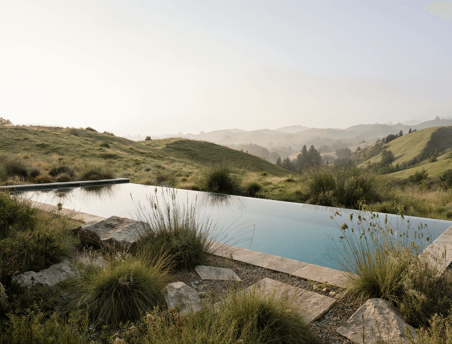 A serene infinity pool integrated into a hillside with expansive valley views.