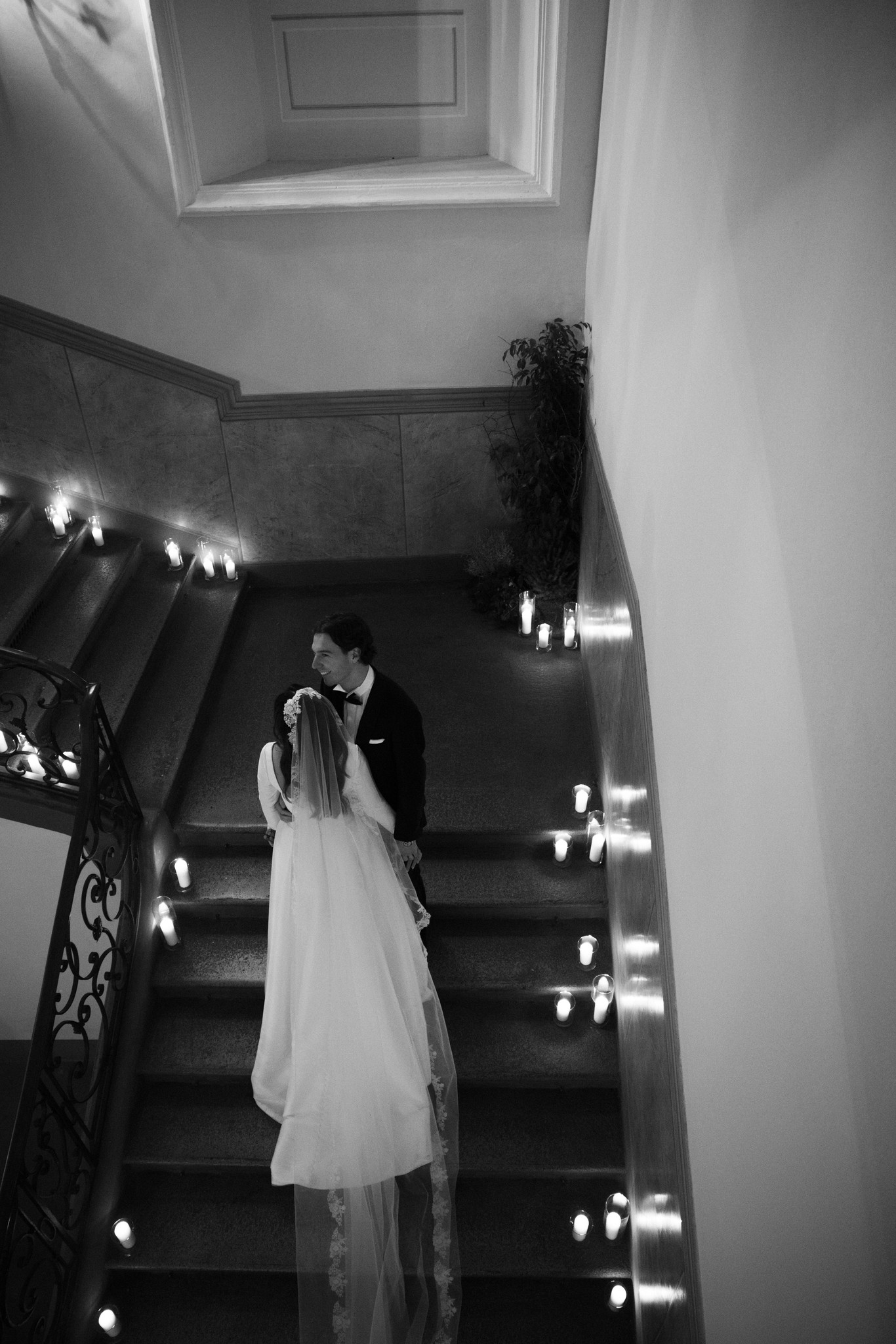 Sposi scendono le scale illuminate del Circolo di Lettura a Parma, reportage di matrimonio in bianco e nero