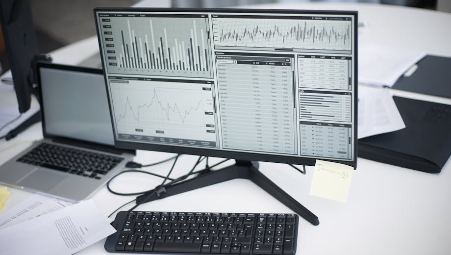 A professional workspace featuring computers and analytical graphs on a monitor, symbolizing modern business environment.