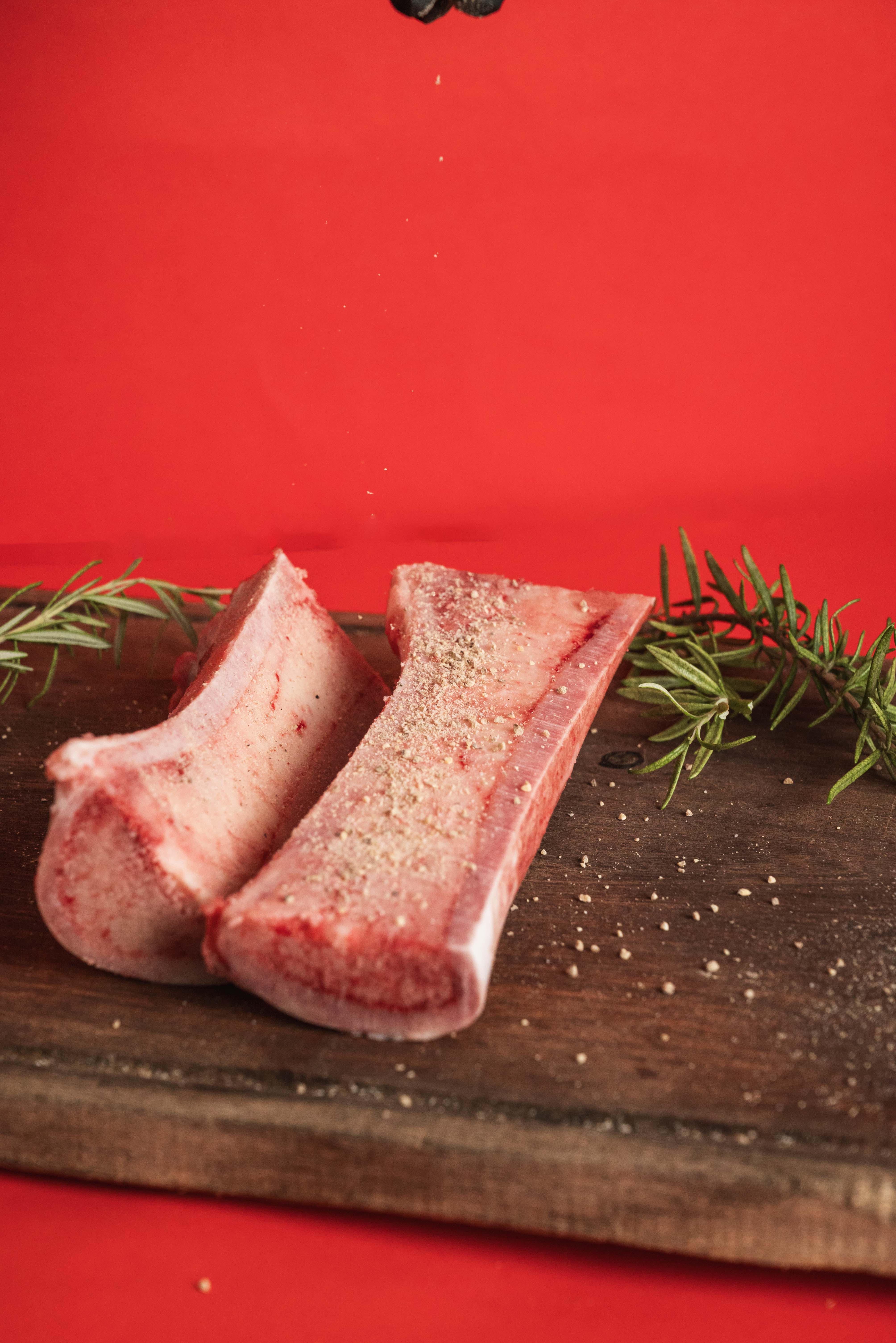two steaks on a cutting board with herbs and spices