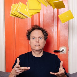 A person pointing and holding yellow towels in a bright room.