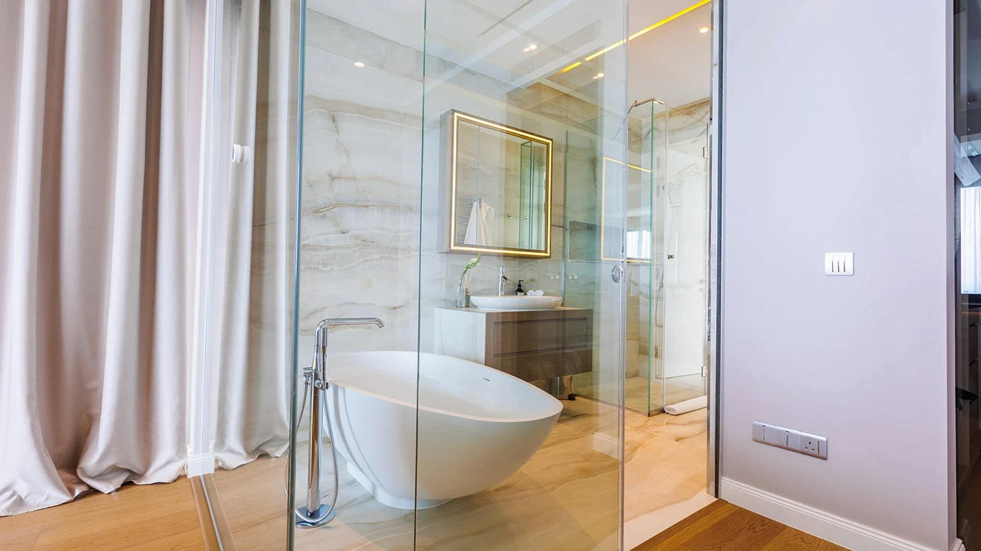 Seafront Residence Limassol spa bathroom with freestanding tub, full-height glass shower, and warm stone finishes