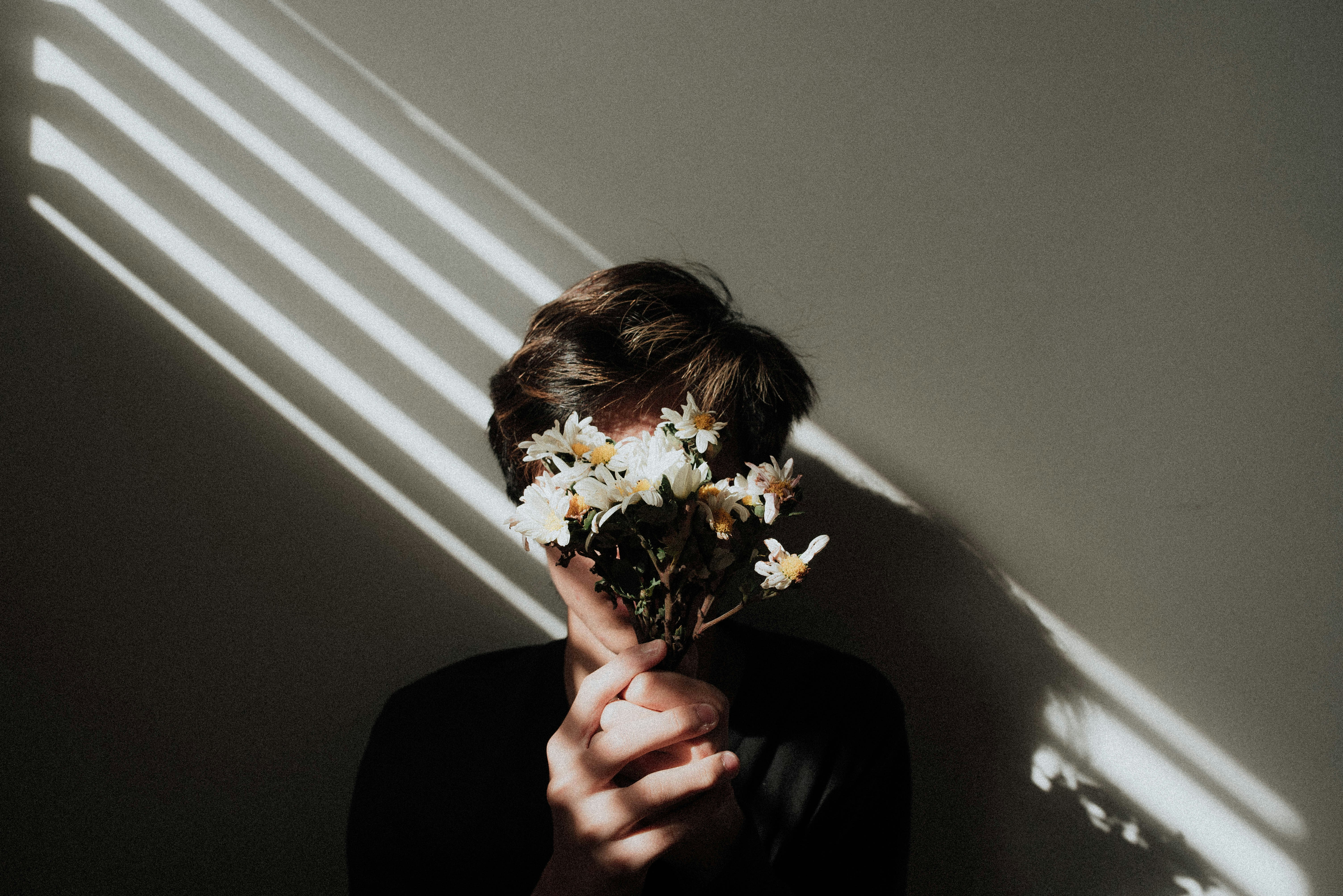 Boy holding daisies with a ray of light