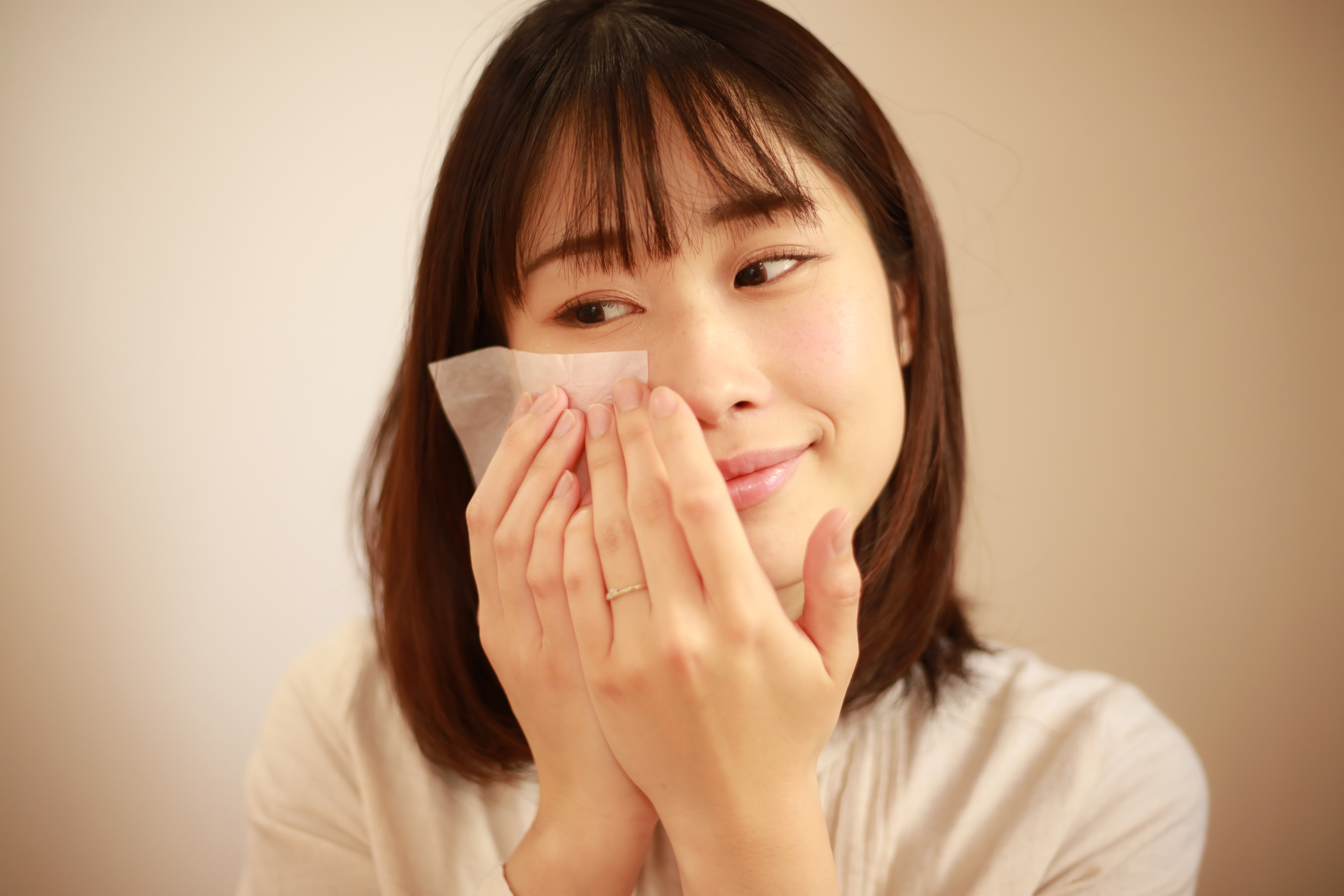 excessive sebum production woman wiping off excess facial oil off her face