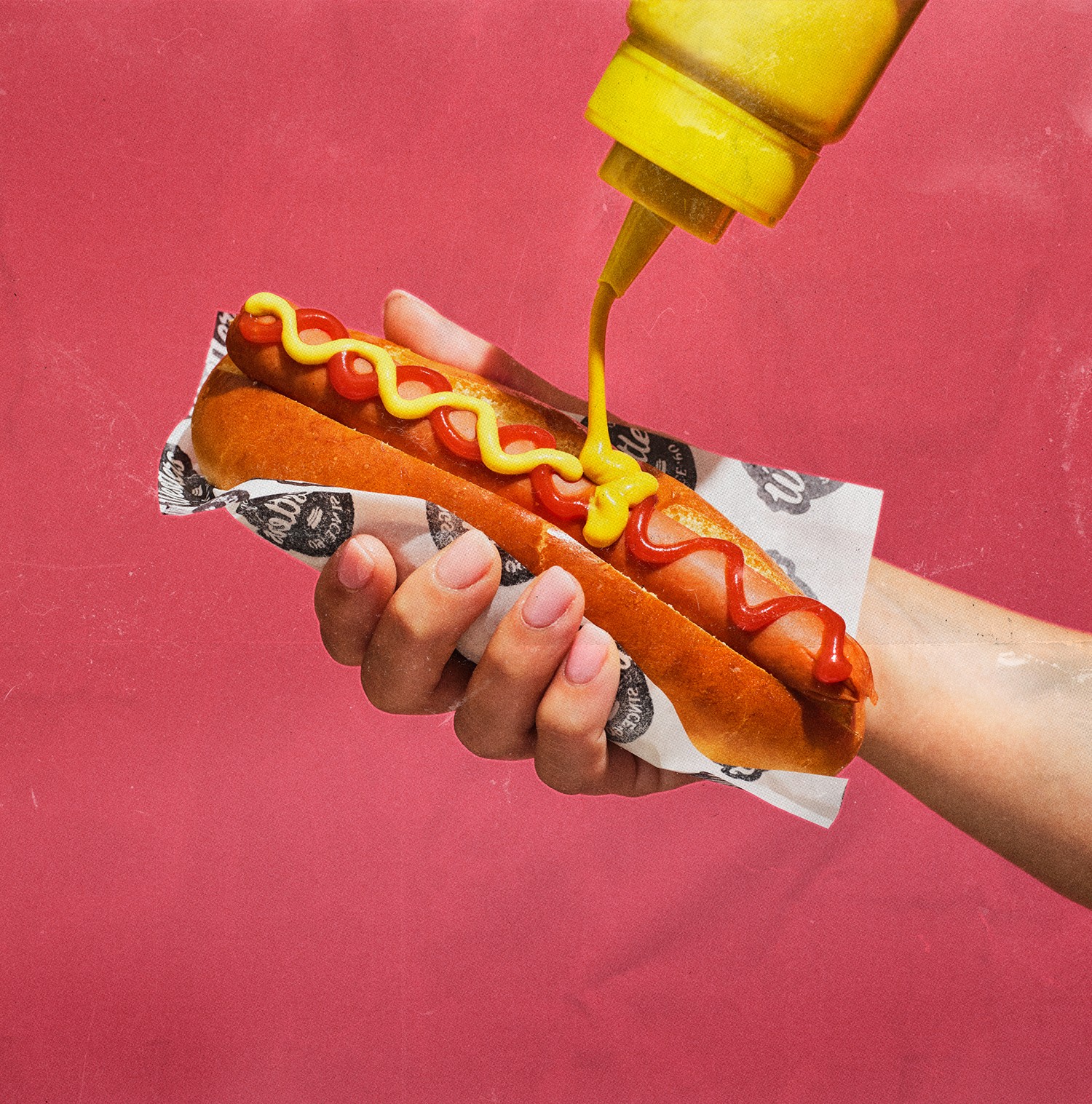 Hand holding hotdog, squirting mustard on hotdog