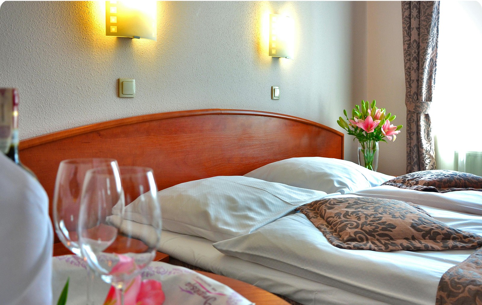 Neatly made hotel bed with white linens, stacked white towels, and soft grey accents, creating a clean and inviting atmosphere.