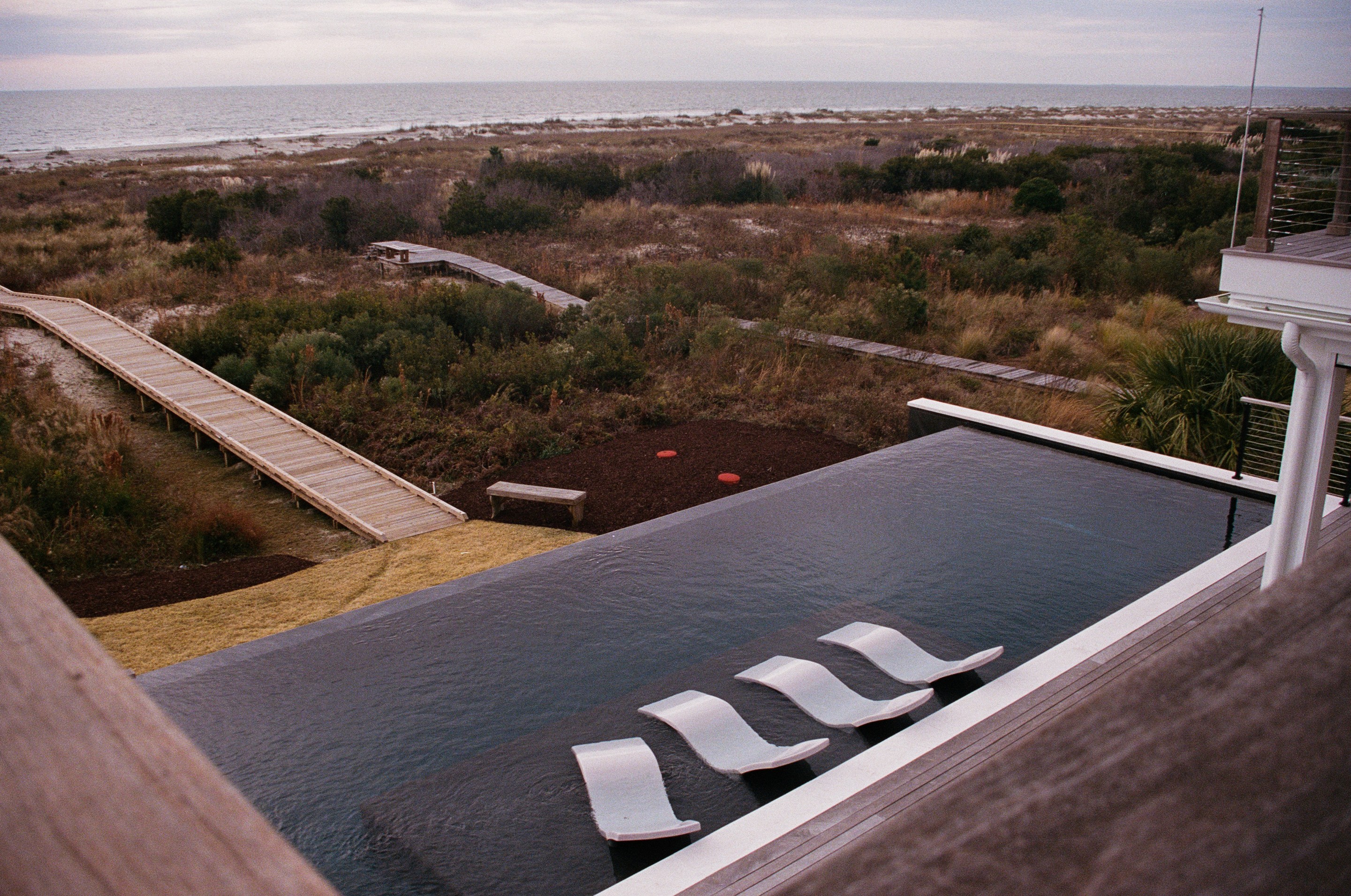Oceanfront pool deck overlooking the beach and open water on a clear day.