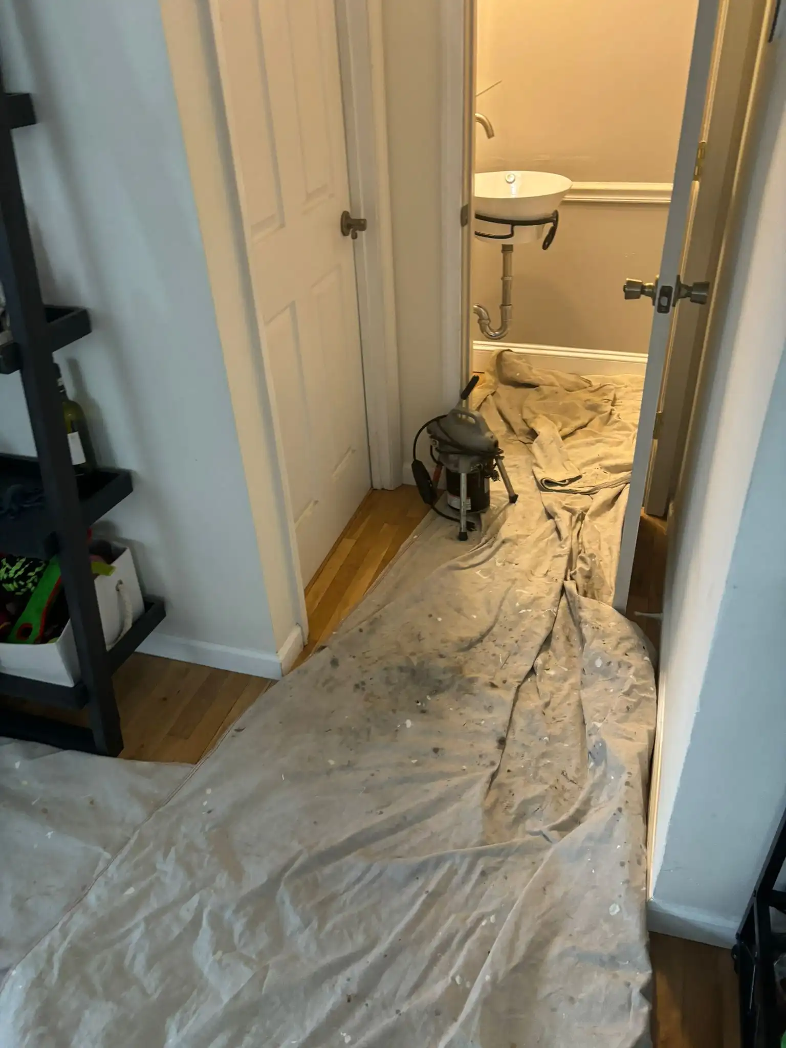 Canvas drop cloths laid over hardwood floors to protect the home during professional sewer line repair services.