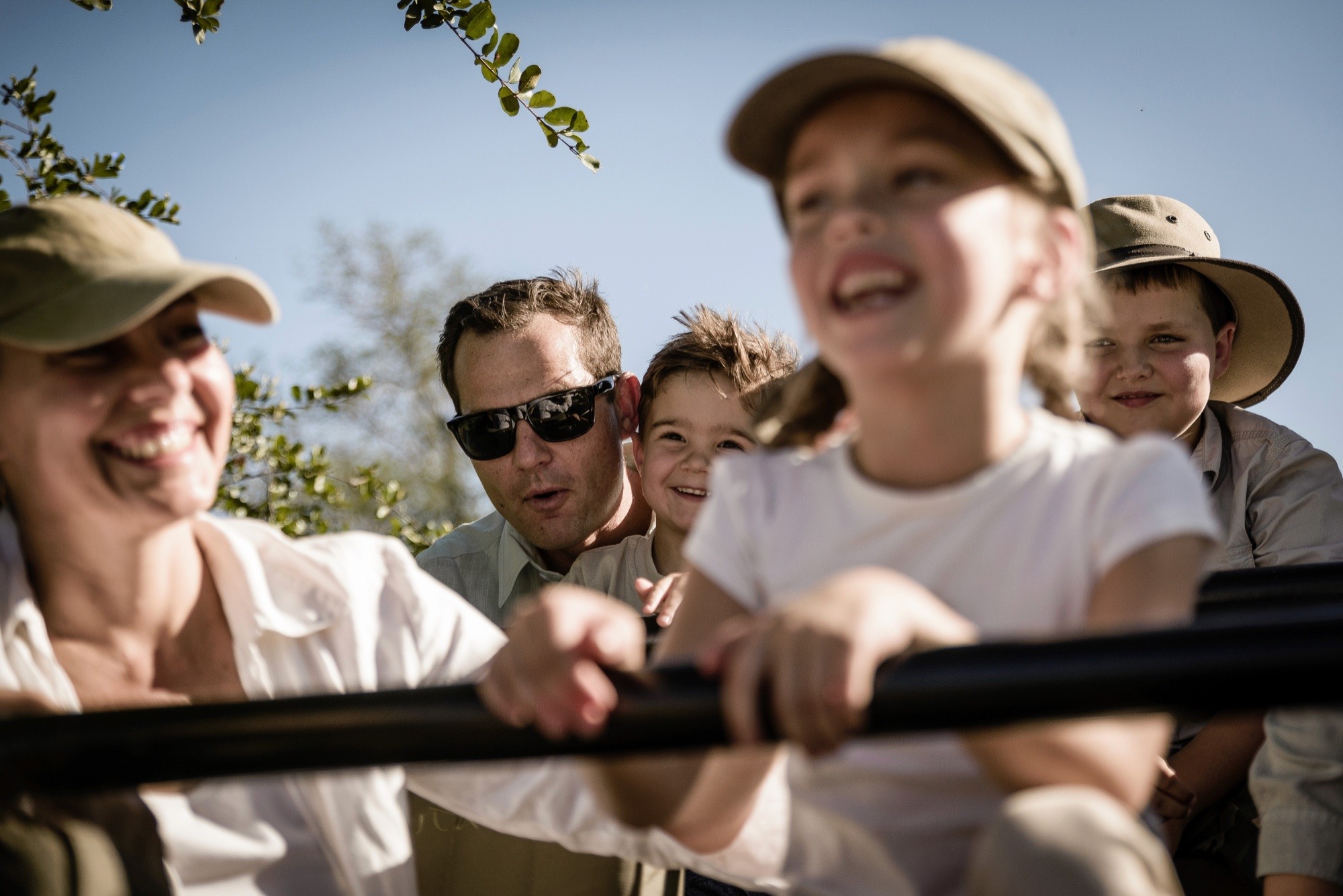 A family laughing together in the back of a safari vehicle